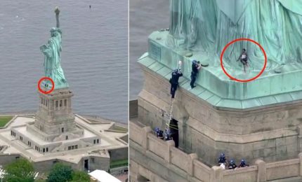 Una donna scala la Statua della Libertà contro Trump